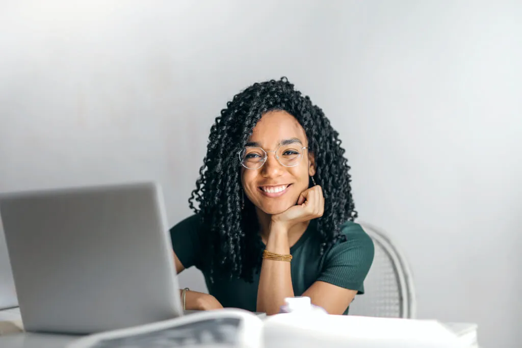 A woman using laptop and smiling towards camera